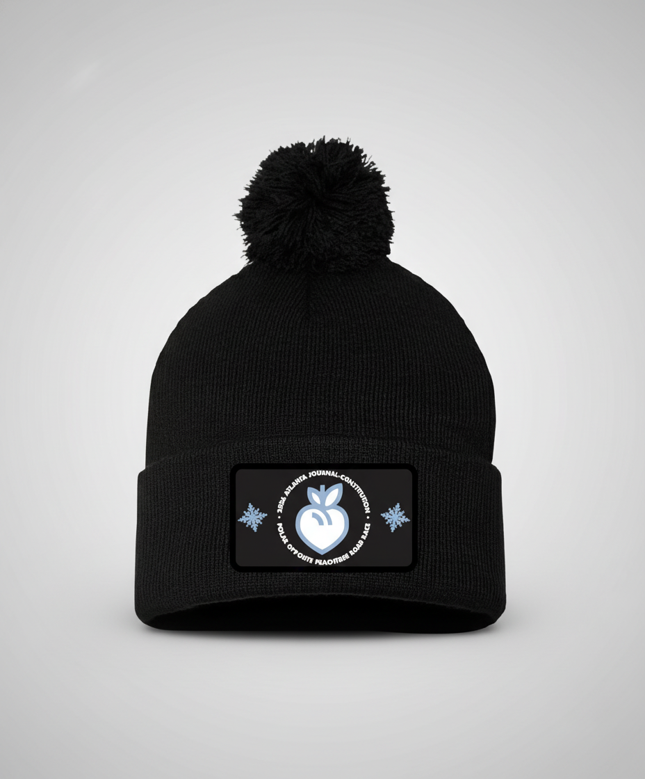 Black beanie with pom-pom and a patch on a white background