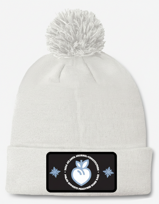 White beanie with pom-pom featuring a black patch on a white background