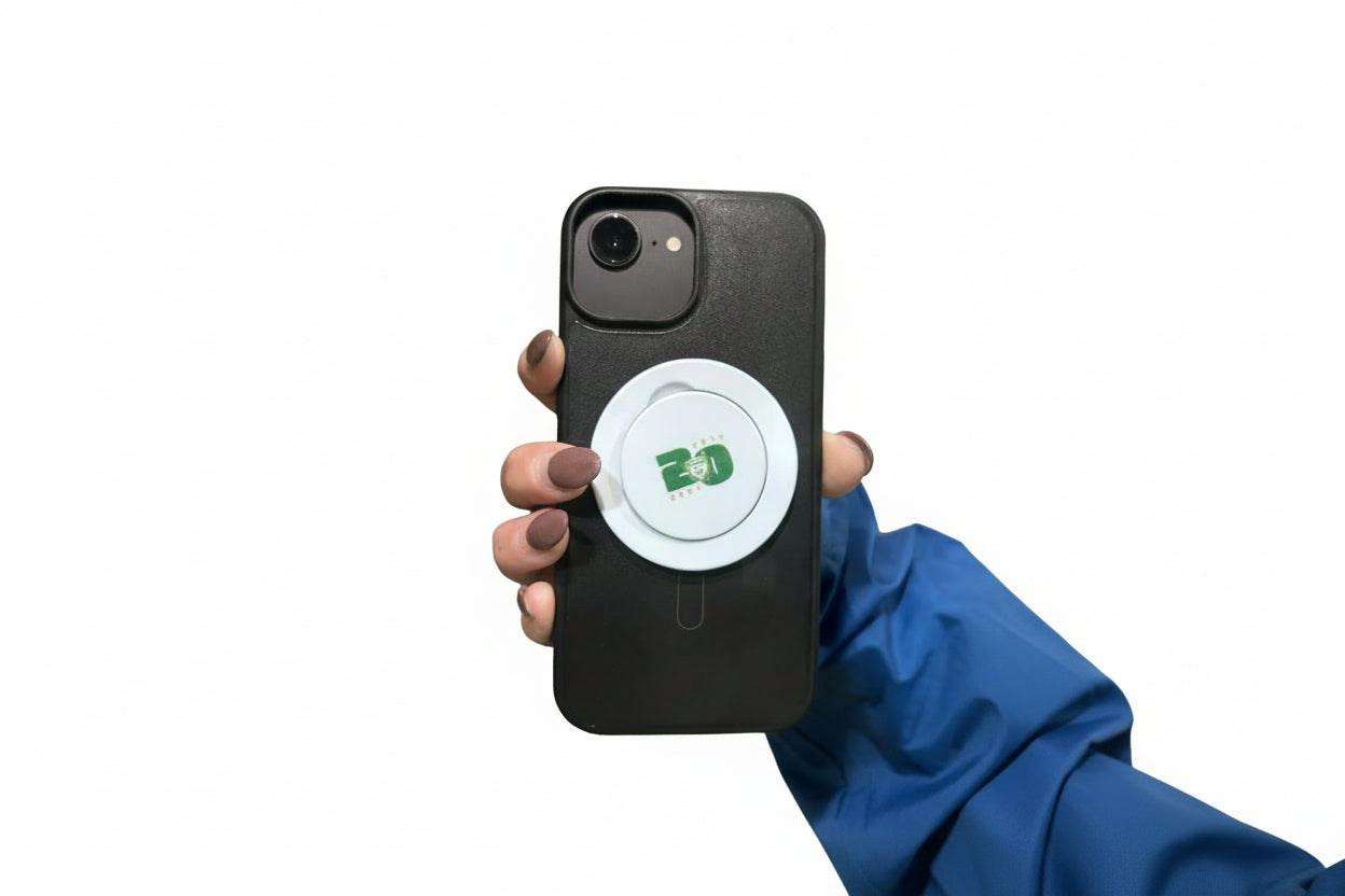 Hand holding a phone with a black case and a white circular object with a logo on it.