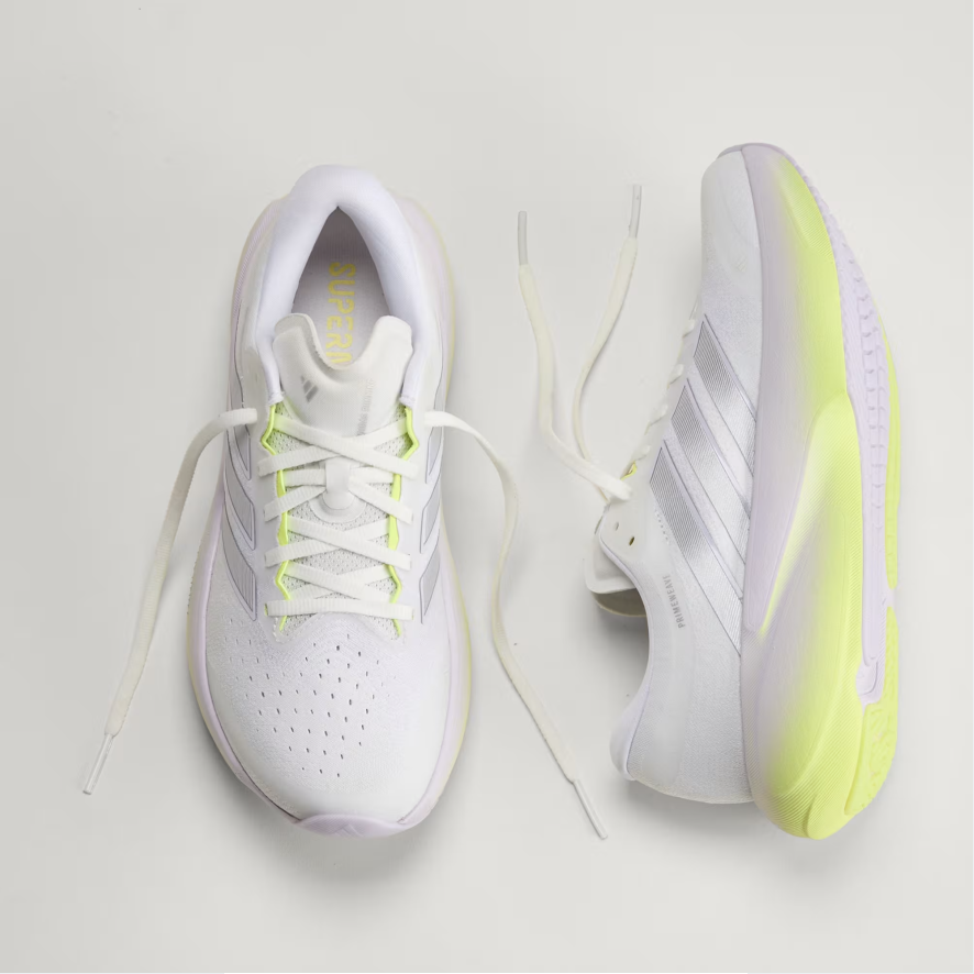 A pair of ADIDAS running shoes in white with neon yellow accents, shown from top and side views on a light gray background.